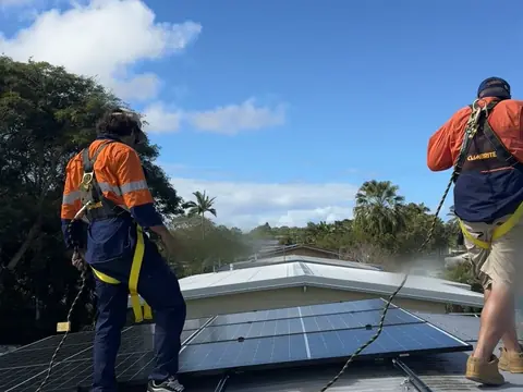 Two of our crew in harnesses on a metal roof next to a group of solar panels