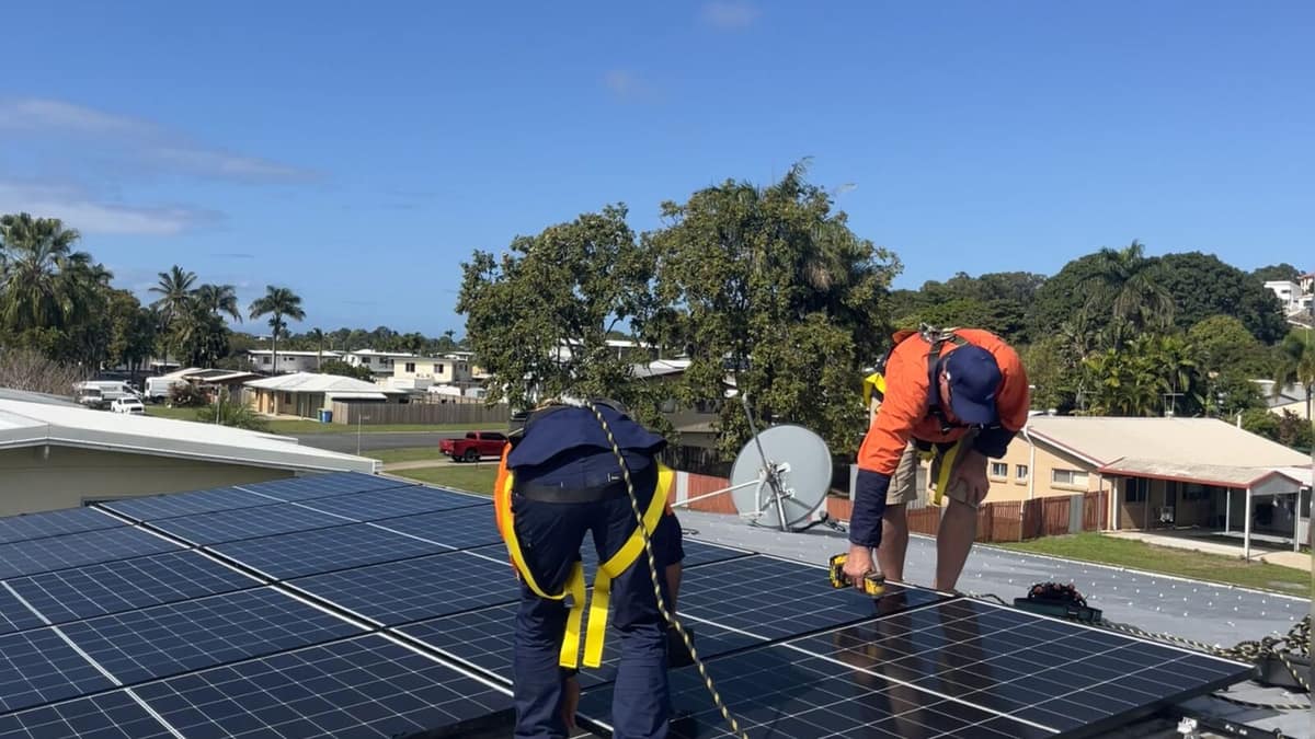 Next Phase Solar technicians working on a rooftop solar array above a Mackay suburb