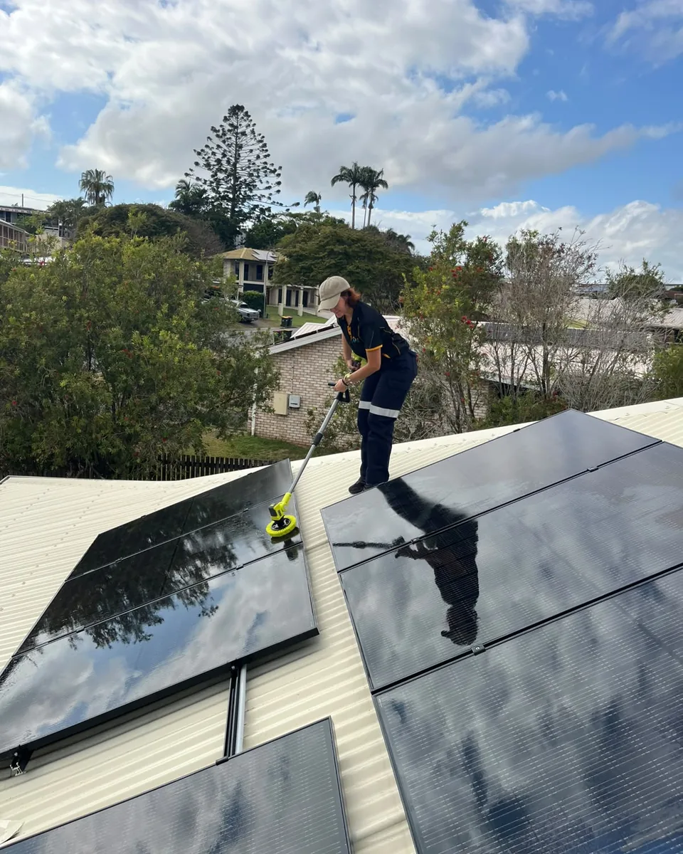 Brenda from Next Phase Solar cleaning solar panels on a roof with a water fed brush