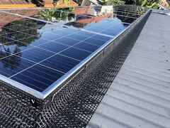 Black mesh fitted around the edge of solar panels on a metal roof