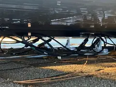 Solar panel cables hanging loose under a panel and lying on the roof