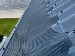Metal mesh gutter guard fitted along the gutter of a metal roof