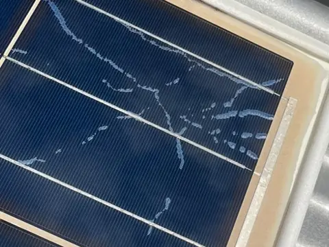 Close up of the corner of a solar panel with fine pale lines running across several cells