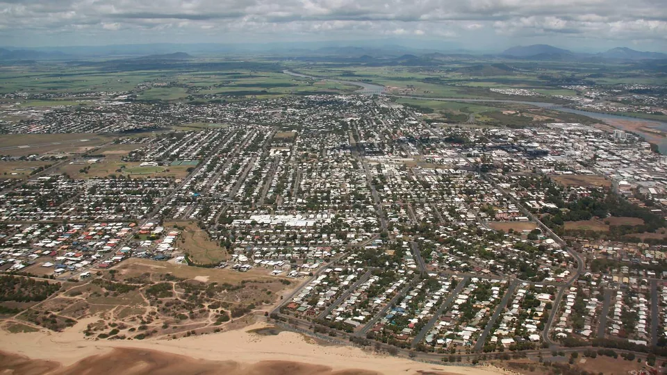 Aerial view over Mackay houses and streets, with farmland behind